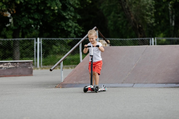 Garoto ativo andando de scooter no parque de skate de verão