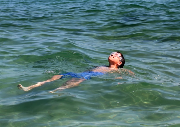 Garoto ativo nadando na água do mar.