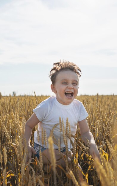 Garoto bonito andando pelo campo de trigo fazendo caretas