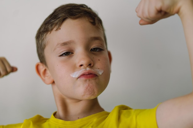 Garoto bonito bebe kefir ou leite retrato engraçado de um garoto com bigode de leite