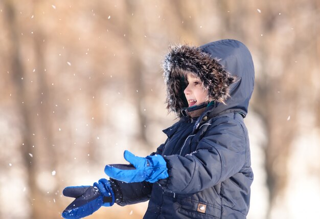 Garoto bonito brincando com neve