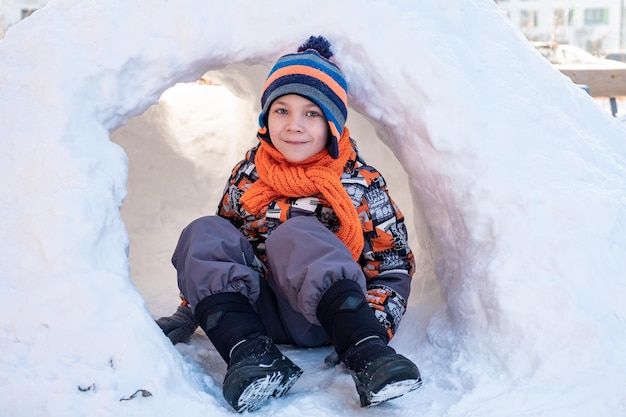 Garoto bonito brincando no iglu do castelo de neve