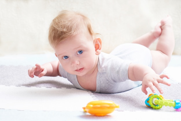 Garoto bonito com olhos azuis está brincando com brinquedo