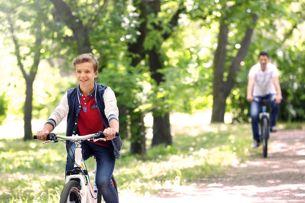 Garoto bonito com pai em passeio de bicicleta no parque