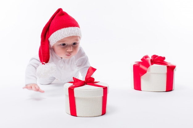 Garoto bonito com presentes de Natal e chapéu de Papai Noel