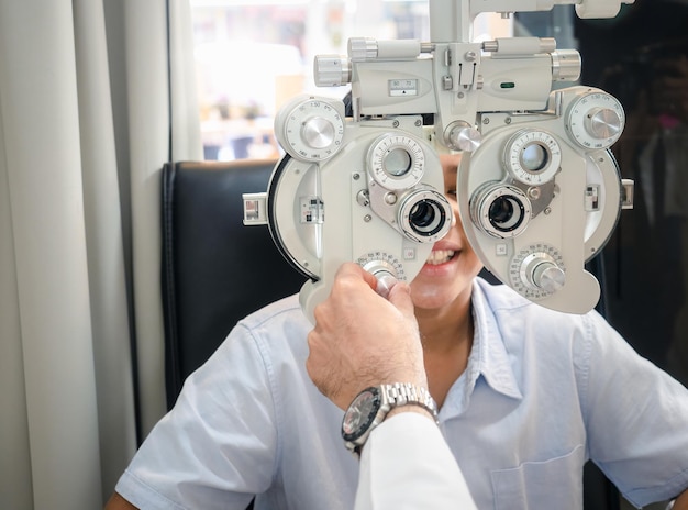 Garoto bonito da Índia sentado em uma loja de óculos com um optometrista especializado em distúrbios oculares e saúde ocular primária procurando uma lente para se adequar à sua visão e obter os óculos mais eficazesxA