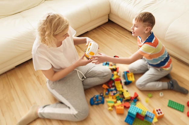 Garoto bonito e sua mãe feliz jogando juntos em casa