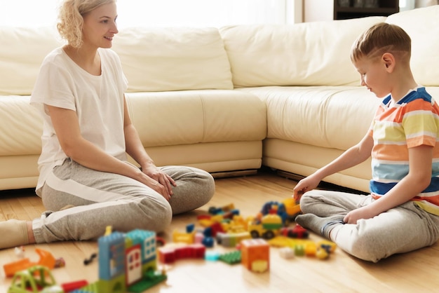 Garoto bonito e sua mãe feliz jogando juntos em casa