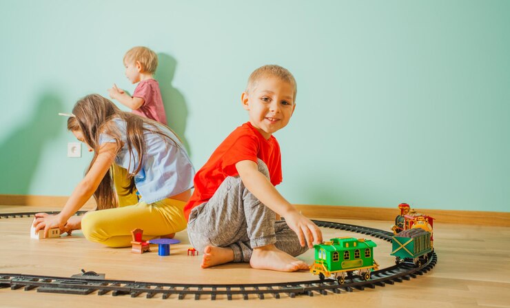 Foto garoto bonito está feliz enquanto brinca com uma ferrovia de brinquedo no chão