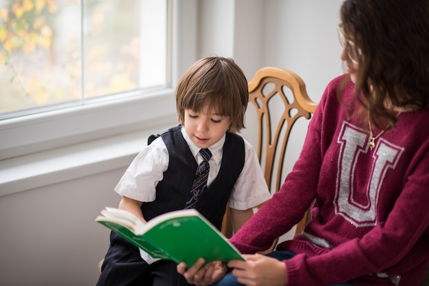 Garoto bonito inteligente com um livro na leitura de cadeira