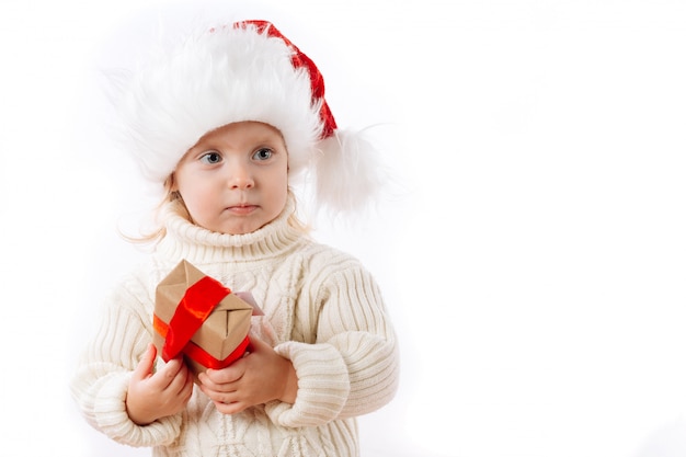 Garoto bonito no chapéu de Papai Noel segurar a caixa de Natal isolada