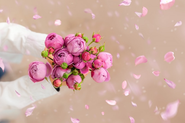 Garoto bonito segurando rosas rosa flores para mãe um com pétalas caindo. Cartão para dia das mães.