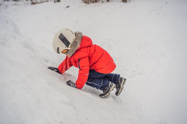 Garoto bonito sobe em uma montanha de neve