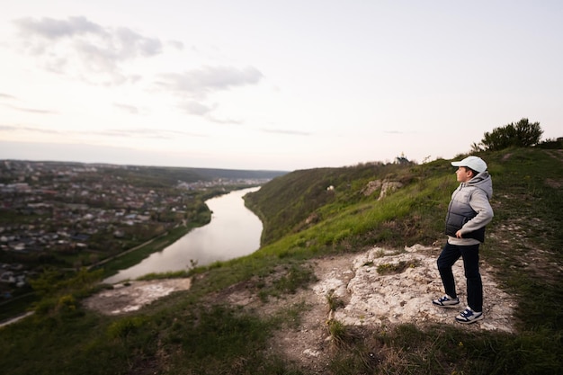 Garoto caminhando de férias fica no topo da montanha olhando para a bela paisagem do desfiladeiro