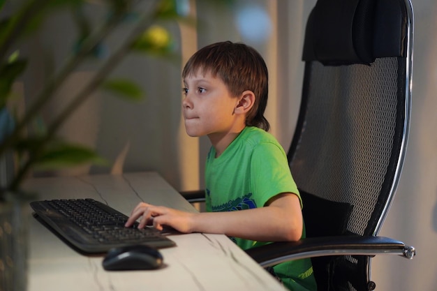 Garoto caucasiano bonito jogando videogame no computador desktop em casa