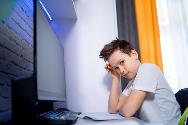 Garoto com aulas de internet em casa em qaurantine. Menino cansado tendo educação em casa.