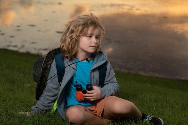 Garoto com binóculos caminhando na natureza Pequeno explorador Recreação ao ar livre e aventuras com crianças Turista infantil no campo ensolarado