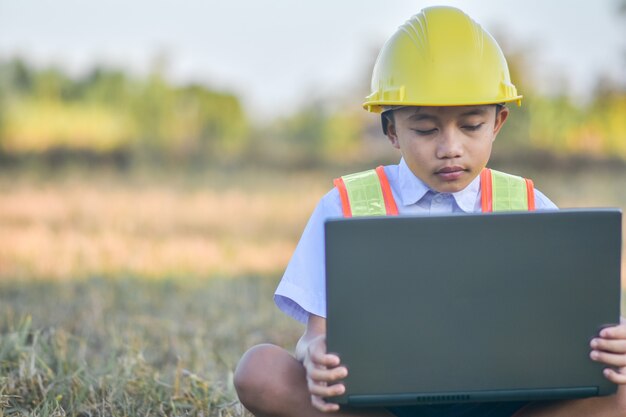 Garoto com capacete amarelo e laptop