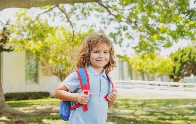 Garoto com mochila indo para a escola conceito de educação infantil com mochilas em pé no parque n