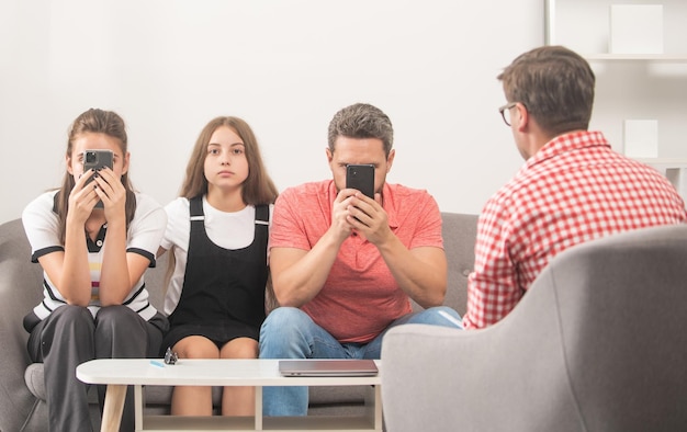 Garoto com pai viciado em telefone e mãe sentada no psicólogo resolvendo problemas, relacionamento