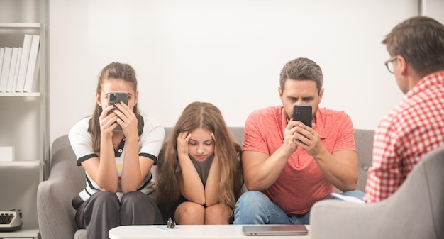 Garoto com pai viciado em telefone e mãe sentada no psicólogo resolvendo vício em problemas