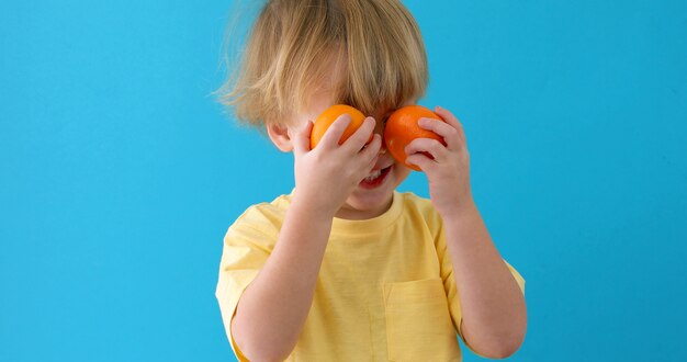 Garoto com tangerinas. menino pequeno com mandarins