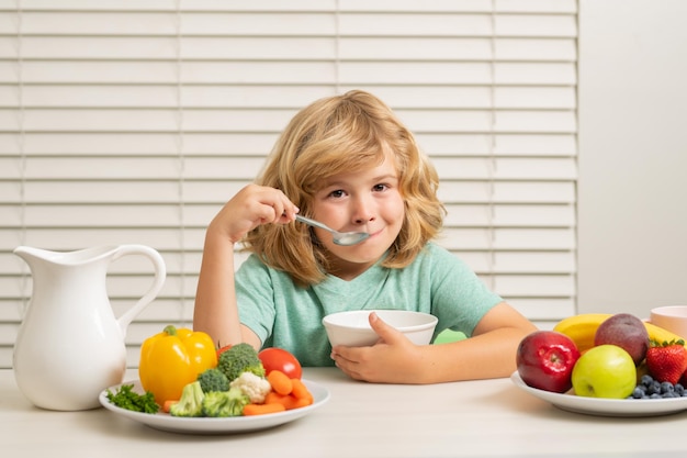 Garoto comendo alimentos saudáveis vegetais café da manhã com leite frutas e legumes criança comendo durante