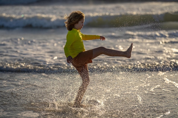 Garoto correndo na praia se divertindo nas férias de verão crianças felizes brincando no mar crianças na natureza com