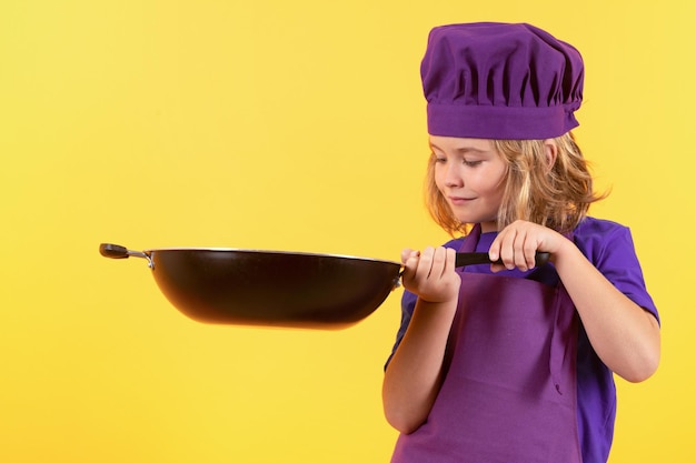 Garoto cozinheiro com panela Criança em uniforme de cozinheiro Chef garoto isolado em fundo amarelo Criança bonita para ser um chef Criança vestida como um chapéu de chef