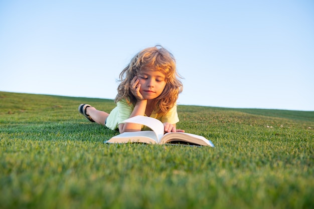 Garoto criança esperta lendo livro no parque ao ar livre em dia de verão crianças espertas