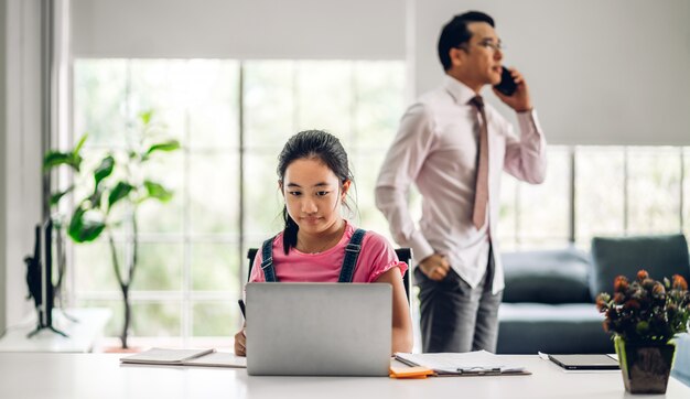 Garoto da escola menina aprendendo e olhando para o computador portátil fazendo lição de casa estudando conhecimento com sistema de e-learning de educação on-line. Videoconferência de crianças com o professor tutor em casa