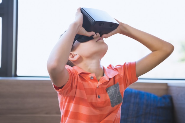 Foto garoto da escola usando óculos de realidade virtual na biblioteca
