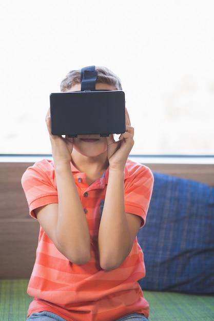 Garoto da escola usando óculos de realidade virtual na biblioteca