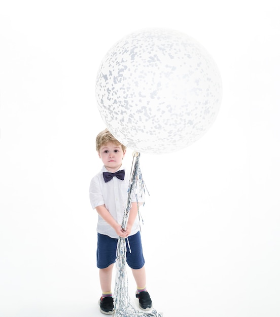 Garoto de camisa branca segura um grande balão. grande balão branco. conceito de celebração. clima de festa. copie o espaço para publicidade. menino espantado segurando um balão voador. preparação para festa de aniversário.