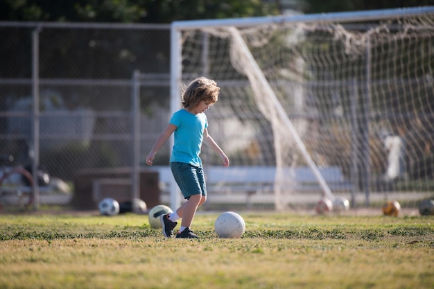 Garoto do futebol Crianças jogam futebol no campo do estádio ao ar livre Garotinho chutando bola Clube esportivo de futebol da escola Treinamento para crianças esportivas Infância e esporte Pequeno campeão de futebol