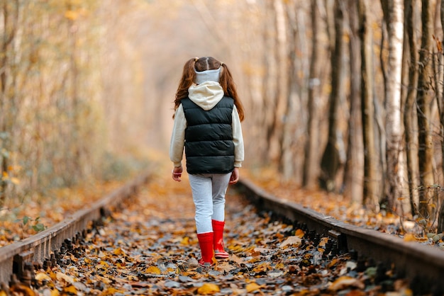 Foto garoto e garota bonitos andando em uma ferrovia sorrindo túnel de amor no outono no lugar romântico do outono