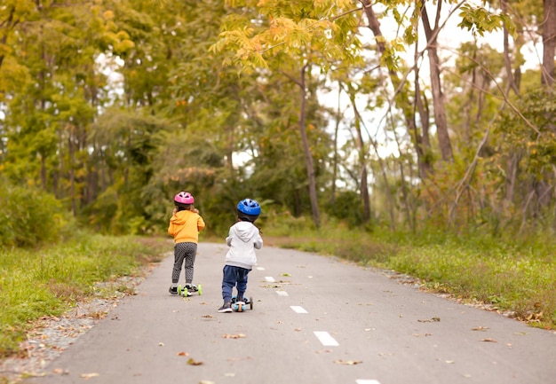 Garoto e garota despessoais estão andando de scooter no parque