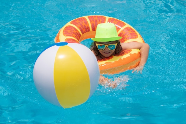 Garoto em óculos de sol na piscina no dia de verão Crianças brincando na piscina Férias de verão e conceito de férias