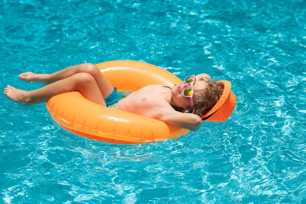 Garoto em óculos de sol na piscina no dia de verão Crianças brincando na piscina Férias de verão e conceito de férias