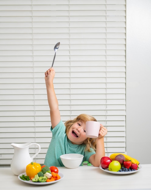 Garoto engraçado, animado e espantado tomando café da manhã com leite, legumes e frutas, nutrição alimentar saudável para