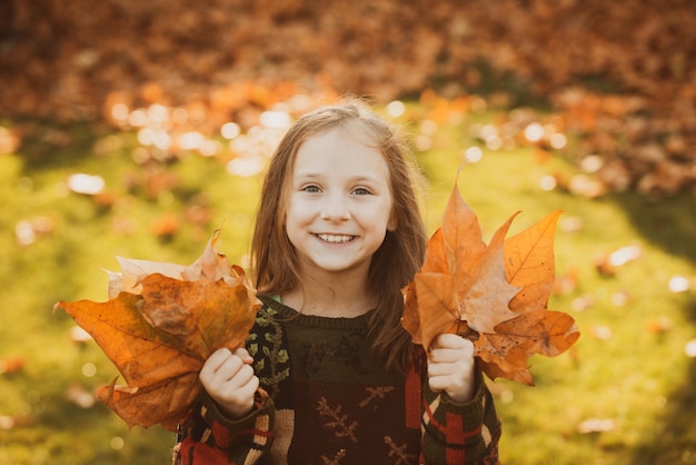 Foto garoto engraçado ao ar livre no outono parque adorável garota feliz brincando com folhas caídas no outono parque beau ...