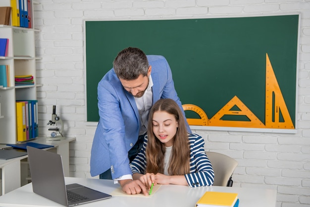 Garoto espantado com professor em sala de aula usa laptop