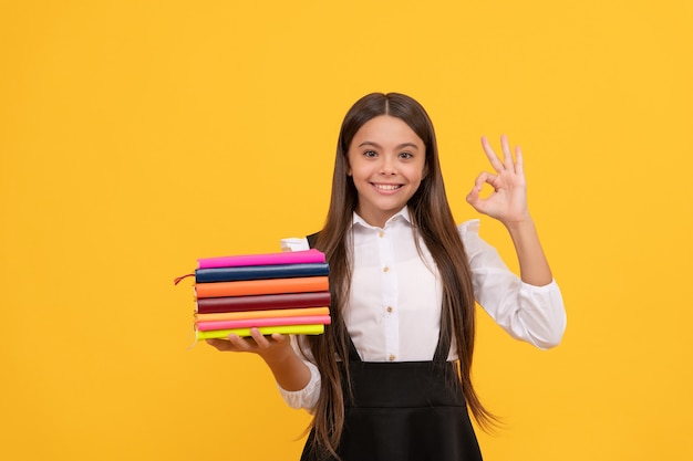 Garoto estudioso na escola primária. menina adolescente feliz segurar a pilha de livros. educação perfeita. de volta à escola. OK. livraria. literatura infantil. criança intelectual oprimida. literatura educacional.