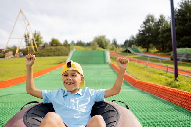 Foto garoto feliz desce em tubo de trenó inflável no parque de diversões