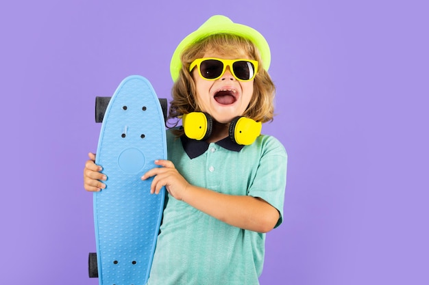 Garoto feliz e engraçado em roupas casuais segurando longboard parecendo feliz e animado Retrato isolado de estúdio de garoto com skate