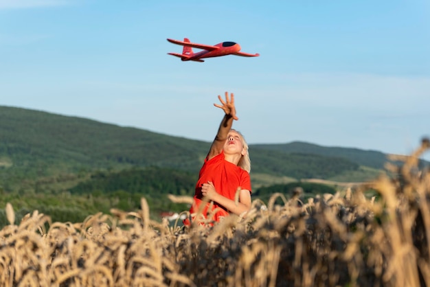 Garoto feliz lança modelo de avião no céu infância feliz e despreocupadaavião de brinquedo vermelho contra o céu azul