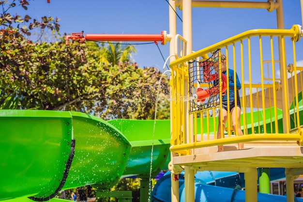 Garoto feliz no toboágua em uma piscina se divertindo durante as férias de verão em uma bela