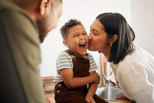 Garoto feliz recebendo um beijo pela mãe carinhosa se unindo e rindo durante o tempo da família em casa jovens pais compartilhando um doce momento de paternidade com seu filho brincalhão relaxando e despreocupado juntos