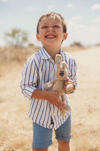 Foto garoto feliz segurando um coelho de brinquedo. lebre.