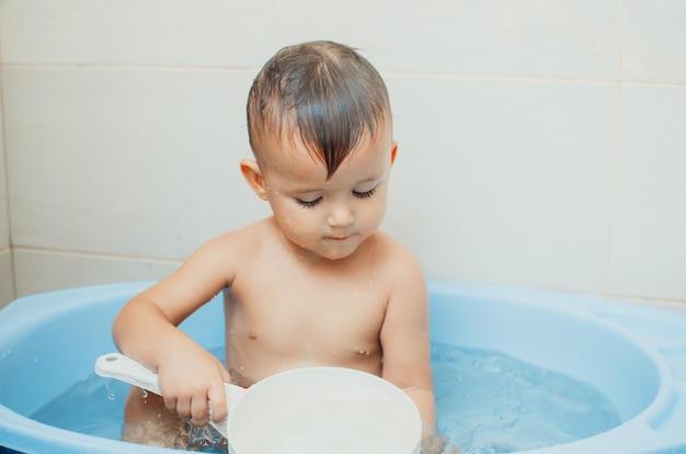 Foto garoto feliz tomando banho, despeje água com um balde branco